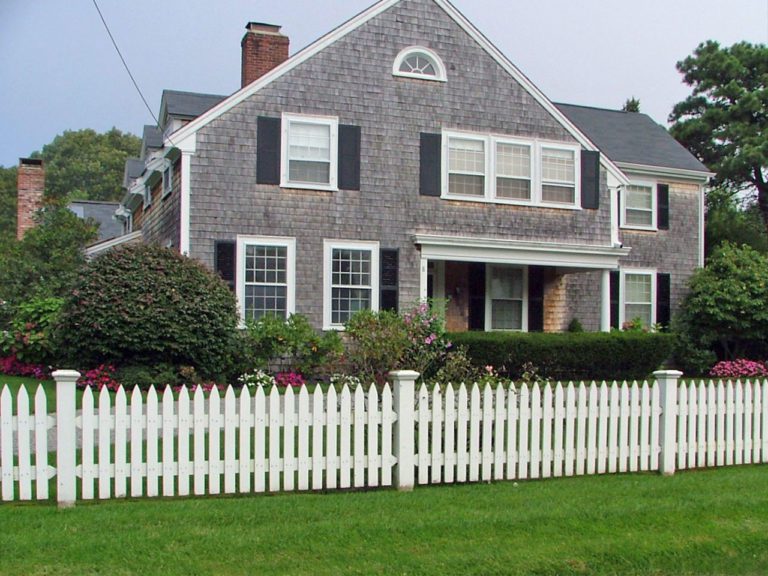 short white picket fence in front of a shingled home