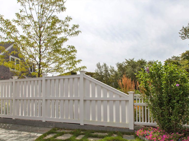 tall white semi-privacy fence in a garden, with a home in the background