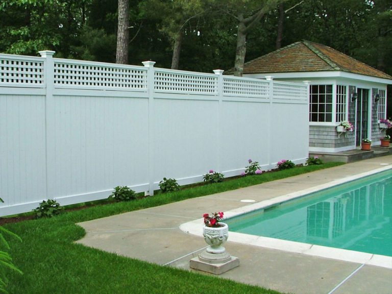 tall privacy fence with a lattice top around a pool, with the poolhouse in the background