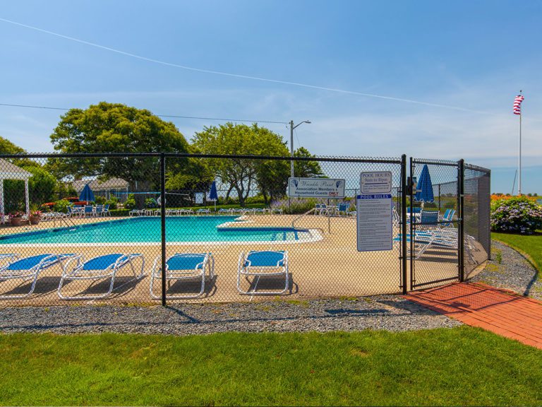 black chain link fence around a pool on a beautiful summer day with an American flag waving in the background