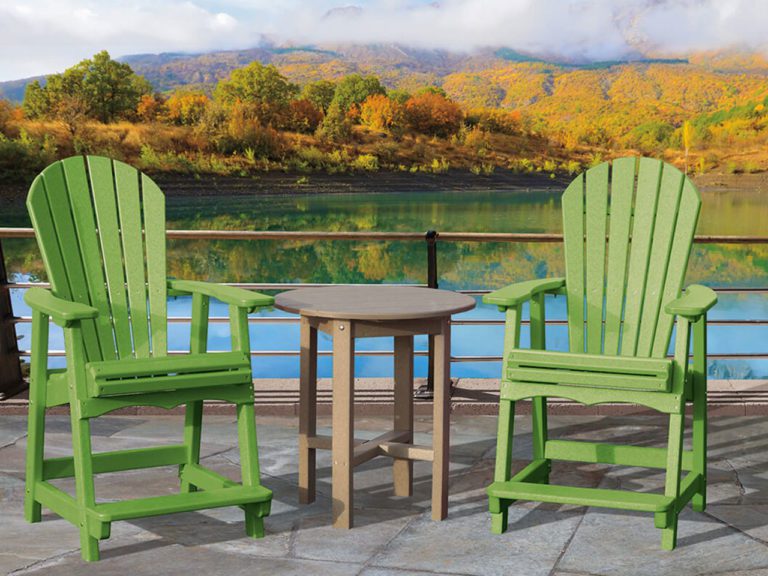 two green poly fanback chairs in front of a lake with autumn foliage in the background