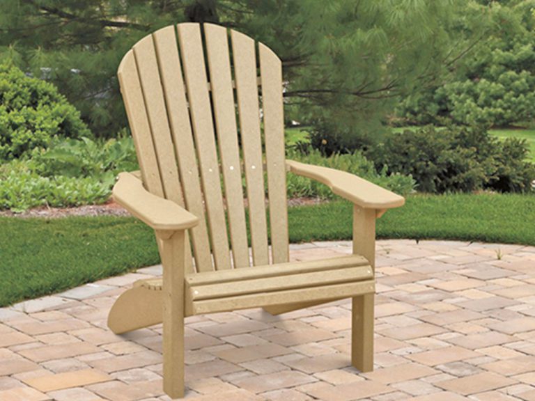 a tan fanback poly chair outside on a patio with trees behind it