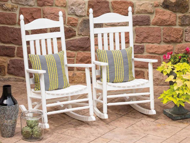two white poly rocking chairs with gray cushions on a stone patio