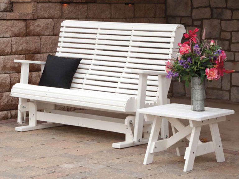 a white poly swing shown against a a stone wall and patio, with a matching accent table and flowers